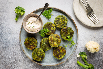 Plate of broccoli and cauliflower fritters or pancakes with sauce, top view