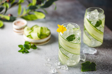 Cucumber infused detox water with mint in a glass with ice. Homemade flavored lemonade on light blue background
