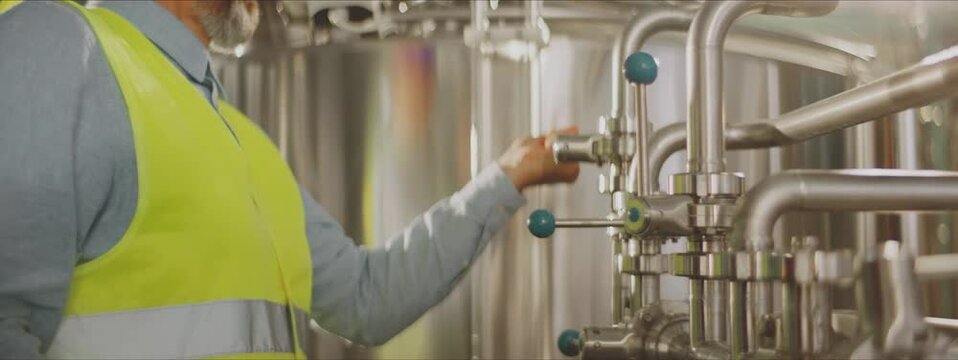 Engineer opening and closing valves on piping using handles. Chemical or food production process control concept.