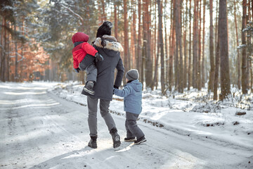 happy family on a walk outdoors in sunny winter forest
