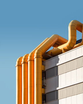 four yellow pipes on white wall outdoor under blue sky