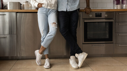 Young black couple in stylish casual clothing posing at home crossing legs in trendy sport shoes....