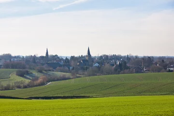 Fotobehang the catholic and protestant church of homberg in winter with sun and green field  © mschauer