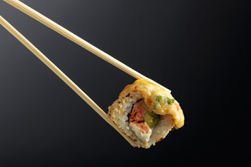 Fresh tasty sushi with wooden chopsticks on a dark background.