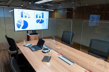 Naklejka premium Video conference meeting room with clear acrylic sheet separates the center on the conference table to prevent COVID-19 and face shield on the table. 