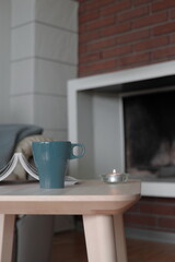 Cup of tea on the table and fireplace in the background 