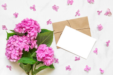 Blank greeting card in petals frame with pink hydrangea flowers bouquet on white background. mock up. flat lay