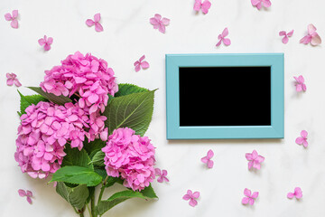 Blank photo frame in petals frame with pink hydrangea flowers bouquet on white background. mock up. flat lay