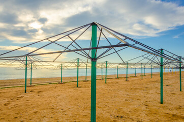 Fototapeta na wymiar Empty frames of canopies without awnings on a winter beach.Umbrellas for shade on an empty beach.