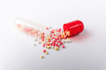 Open pill in the form of a capsule with scattered contents on a white background close-up.