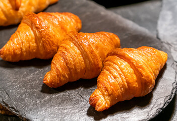 Plain croissants on black rock plate.