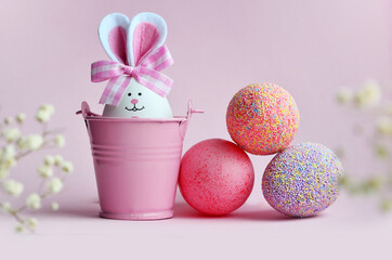 Easter holiday concept with cute handmade eggs, bucket and bunny ears.
