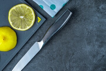 Sliced lemon on a cutting plastic board and a silver knife on a marble table background. Close-up.
