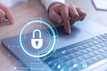 A programmer is typing a code on computer to protect a cyber security from hacker attacks and save clients confidential data. Padlock Hologram icons over the typing hands. Formal wear.