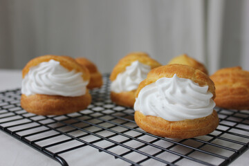 Delicious Homemade small cakes profiterole choux pastry with custard (Choux Cream) on the black rectangle sieve, On a table with copy space for text and blur background.