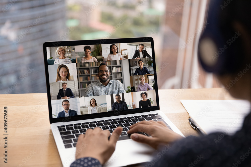 Wall mural over shoulder view of female in headset take part in distant virtual briefing video conference using