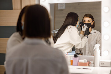 Naklejka premium Professional brow master is doing her job for beautiful caucasian woman at beauty salon