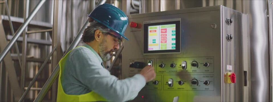 Senior process engineer adjusting settings on control panel. Chemical or food production process control concept.