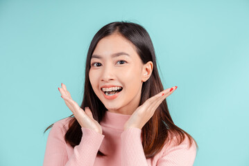 Dental braces of young asian woman wearing retainer braces glad emotion with white teeth increase confidence for healthy on blue background isolated, Happiness teenager smiling facial expression.