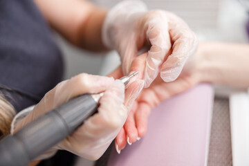 Professional manicure master is doing nails for happy client in beauty salon