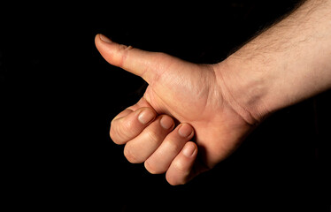 Closeup of male hand showing thumbs up sign against black  background