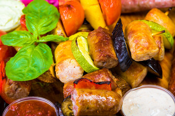 hot browned ruddy homemade sausages on a wooden tray with sauces and vegetables