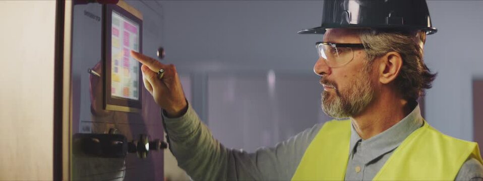 Side view of man in hardhat copying values from control panel. Chemical or food production process control concept.