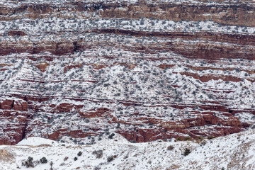Close up of red rock mountainside covered in snow on overcast day in rural New Mexico