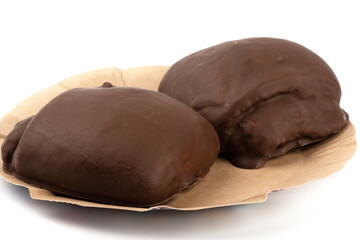 Two sweet buns in chocolate glaze on a paper plate over a white background.