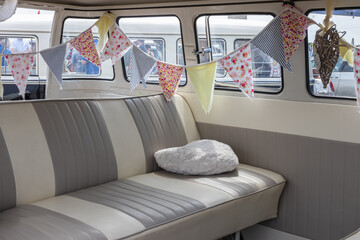 The interior of a camper van with leather seating and bunting - Powered by Adobe