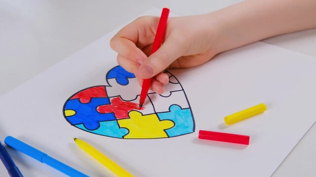 World Autism Awareness day. Children's hand draws heart from multi-colored puzzles. Mental health care concept