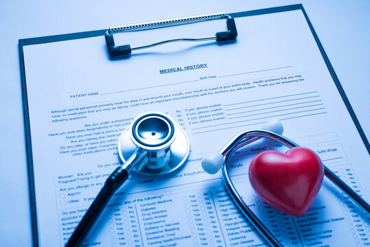 Close Up Photo Of Patient Medical History Card On The Clipboard Stethoscope Equipment And Small Red Heart