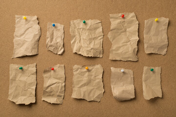 Collection of different size shape crumpled craft pieces of paper attached with colorful pins to the wooden backdrop