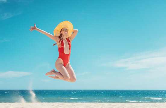 Beautiful woman enjoying her beach vacation jumping high