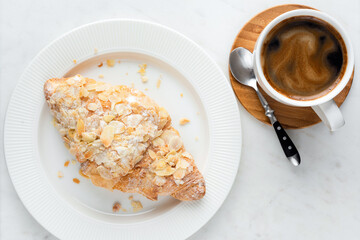 Coffee cup and almond croissant on white marble table. Coffee break, morning breakfast food