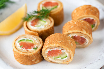 Obraz na płótnie Canvas Salmon and cream cheese crepe rolls. Appetizer rolls with smoked salmon, cucumber and cream cheese with dill