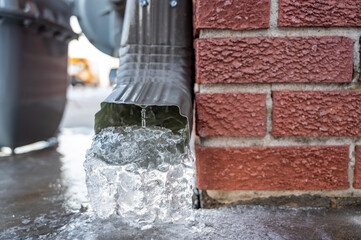 Metal downspout jammed with a frozen ice block