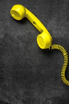 Yellow retro telephone with wire on gray marble background. Vertical position