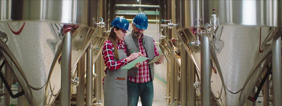 Senior process engineer describing important process parameters to junior female colleague. Chemical or food production process control concept.