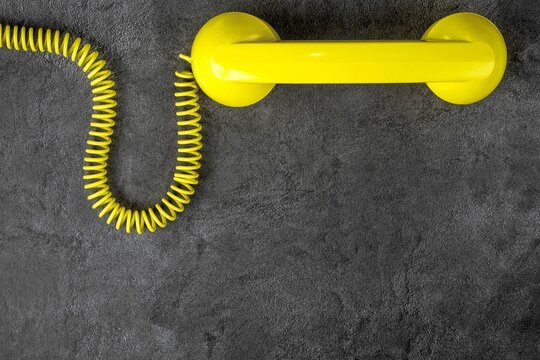 Yellow retro telephone with wire on gray marble background. Horizontal position