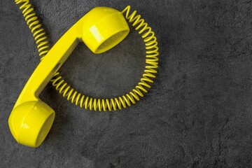 Yellow retro telephone with wire on gray marble background. Horizontal position