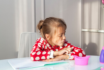 child girl doing homework sitting at kitchen table,  learning at home