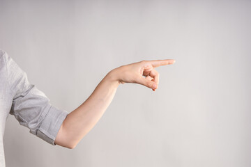 Hand gestures, Poke your finger, point to the side. businesswoman in a casual gray shirt makes a hand gesture