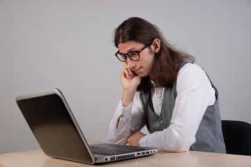 bored student is sitting at a laptop. Guy is a geek gamer, uses a laptop. Uninteresting course, boredom and procrastination.