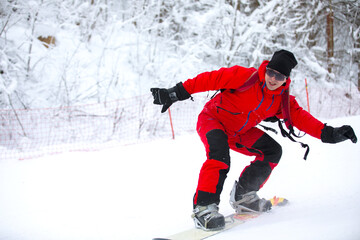 Fototapeta na wymiar Snowboard rider riding snowboard fast down steep snowy mountain slope, white snow on clowdy winter day.
