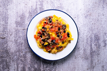 Traditional pasta with black olives and tomato