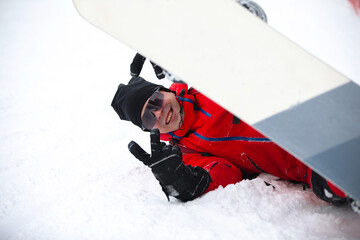 Snowboard under his snowboard posing.