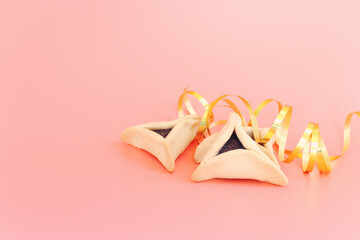 Purim celebration concept (jewish carnival holiday). Hamantaschen cookies over pastel pink background