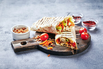 Eastern traditional shawarma with chicken and vegetables, Doner Kebab with sauces on wooden cutting...