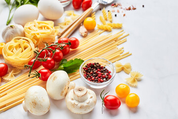 Food background with place for text, with different kinds of pasta, tomatoes, herbs, mushrooms, eggs, seasonings scattered on light marble background. Italian cuisine concept